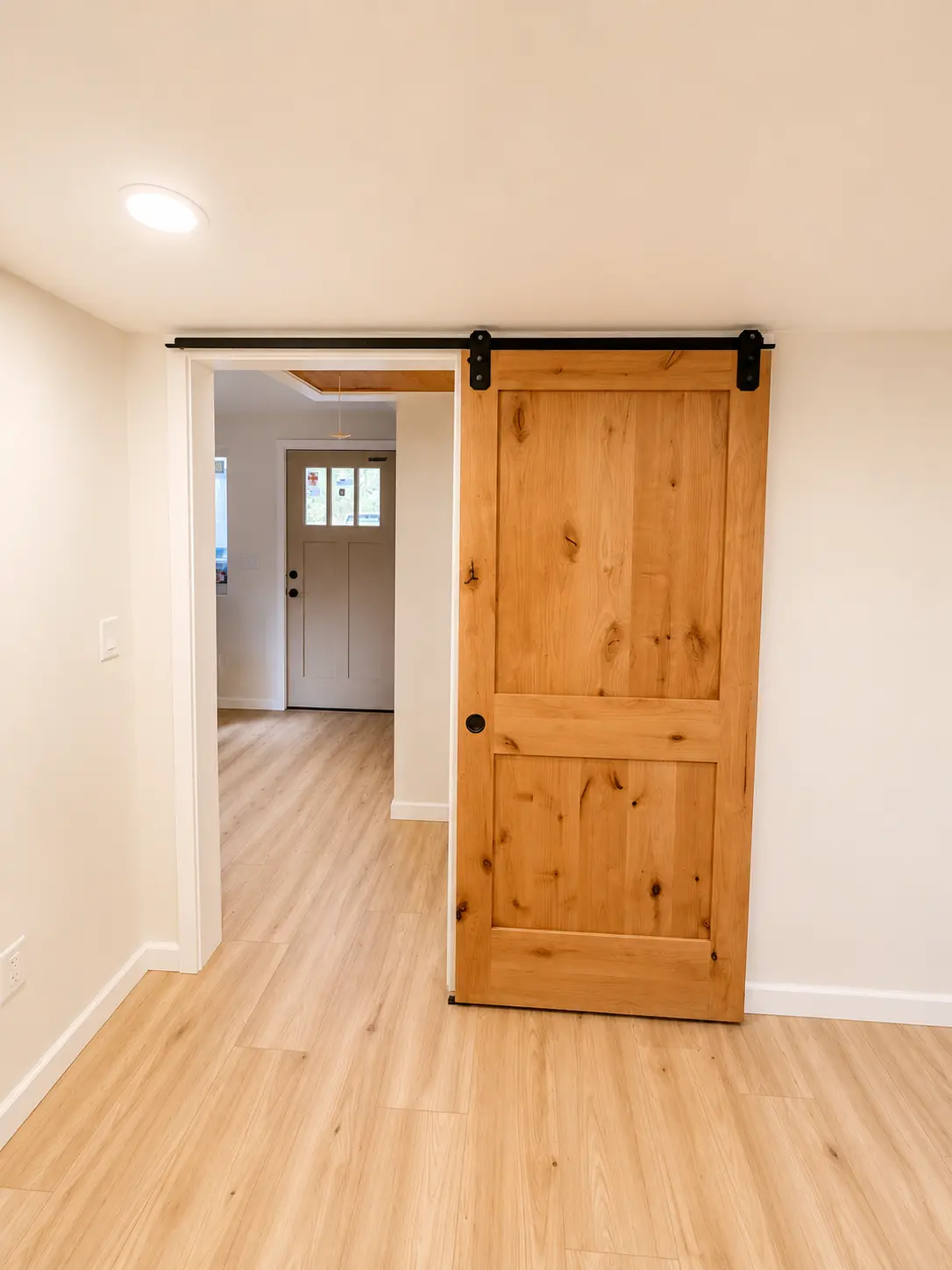 Natural wood sliding barn door installed in a finished room